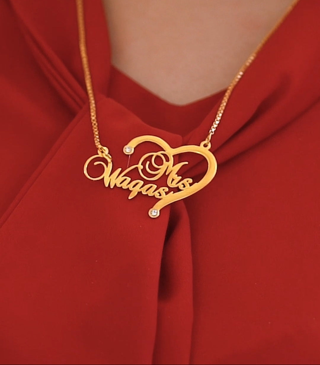 Gold necklace with a heart-shaped pendant on a red fabric background