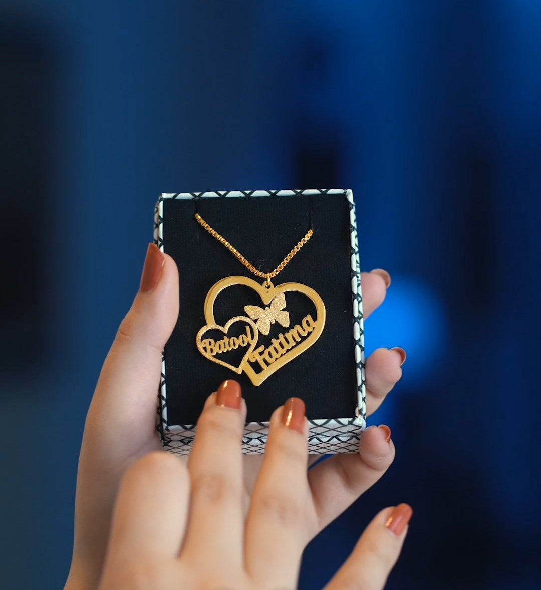 Hand holding a necklace with a heart design and 'mibbilux.com' branding.