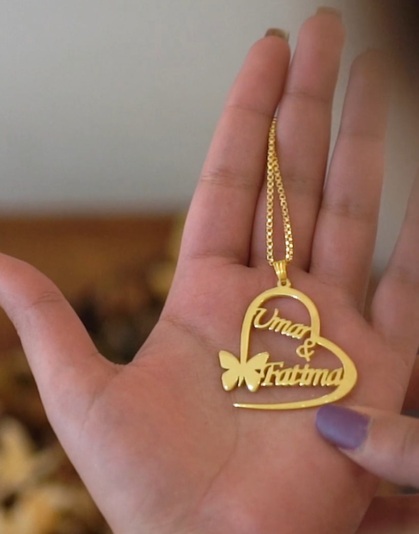 Gold heart-shaped necklace with 'Omar & Fatima' on a hand