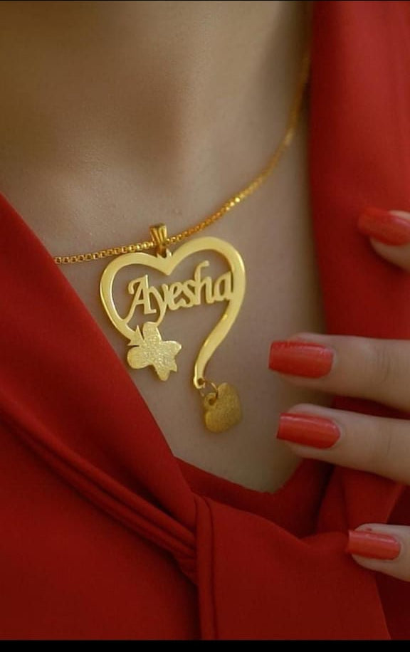 Gold necklace with a heart-shaped pendant displaying 'Ayesha' on a red background
