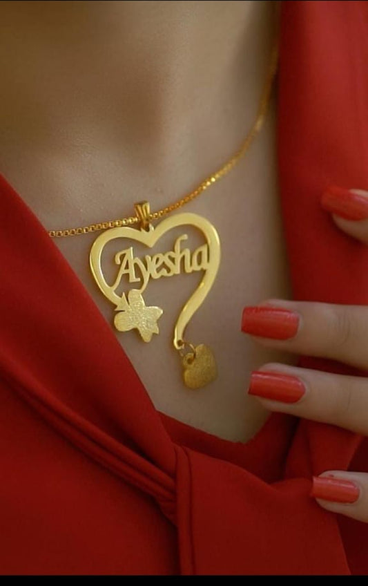 Gold necklace with a heart-shaped pendant displaying 'Ayesha' on a red background