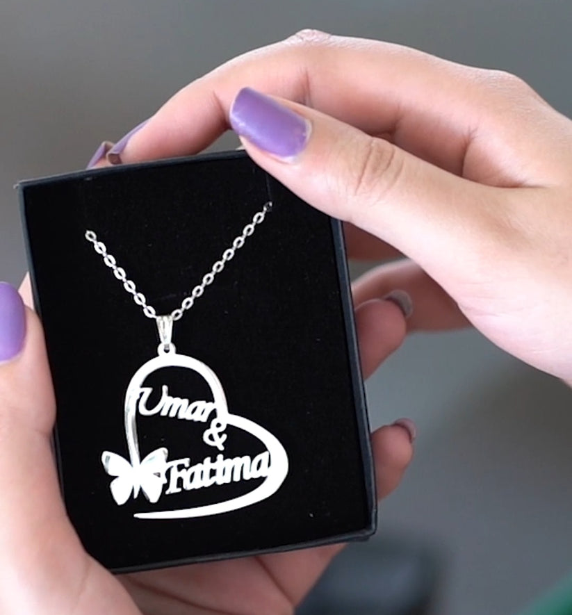 Heart-shaped necklace with 'Umar & Fatima' engraving held by a hand with purple nail polish.