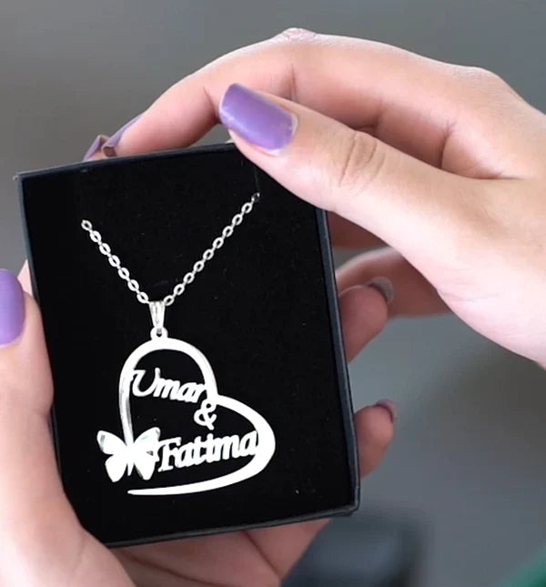 Heart-shaped necklace with 'Umar & Fatima' engraving held by a hand with purple nail polish.